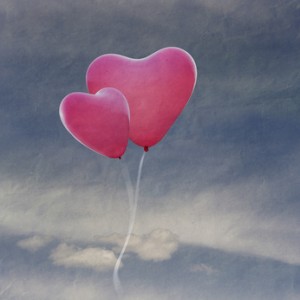 two balloons in the shape of heart flying in the sky with clouds